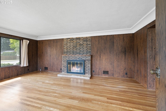 107 NW 10th Ave, Canby, OR 97013 - unfurnished living room with wood walls, light wood-style floors, a textured ceiling, and a fireplace
