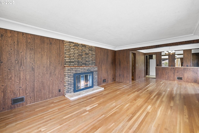 107 NW 10th Ave, Canby, OR 97013 - unfurnished living room with wooden walls, a brick fireplace, a chandelier, wood finished floors, and crown molding