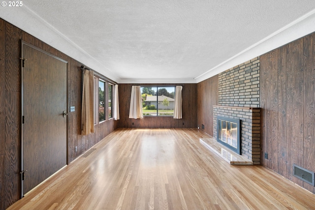 107 NW 10th Ave, Canby, OR 97013 - unfurnished living room featuring wooden walls, a textured ceiling, light wood-type flooring, and a fireplace