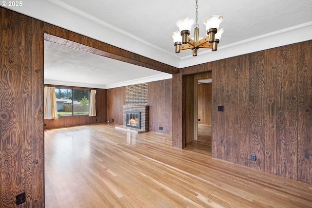 107 NW 10th Ave, Canby, OR 97013 - unfurnished living room with a chandelier, wood walls, light wood finished floors, and a fireplace