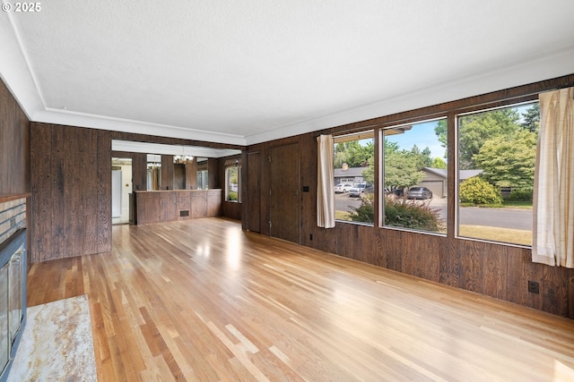 107 NW 10th Ave, Canby, OR 97013 - unfurnished living room featuring wood walls, light wood finished floors, a brick fireplace, and a chandelier