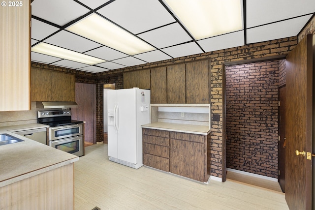107 NW 10th Ave, Canby, OR 97013 - kitchen featuring white refrigerator with ice dispenser, double oven range, light countertops, brick wall, and a paneled ceiling