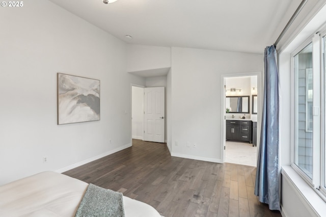 unfurnished bedroom with connected bathroom, dark hardwood / wood-style floors, and lofted ceiling