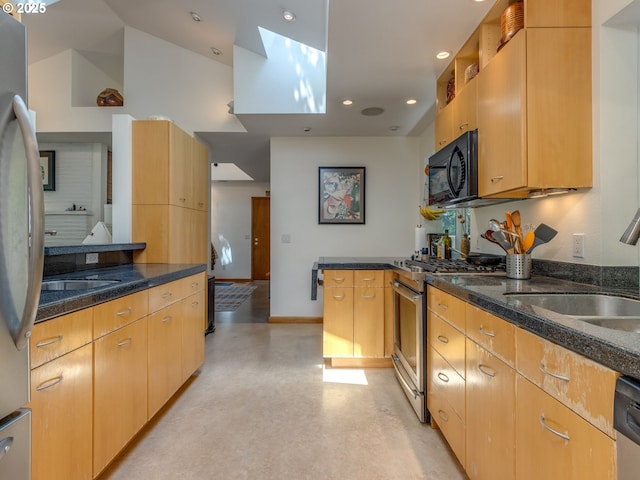 6310 NE 31st Ave Unit A, And B, Portland, OR 97211 - kitchen with stainless steel appliances, dark stone counters, a sink, baseboards, and a peninsula