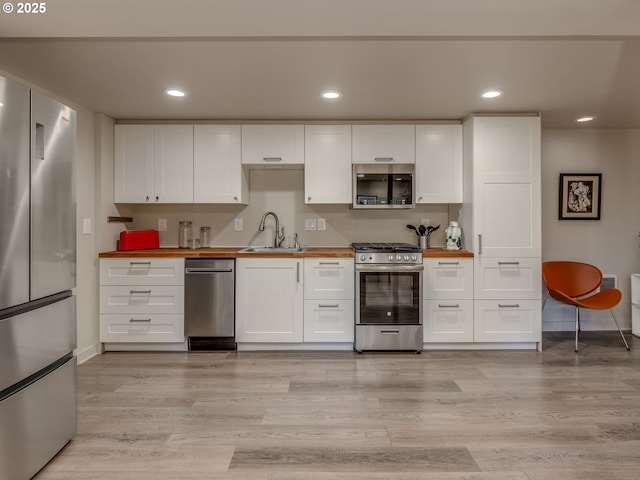 6310 NE 31st Ave Unit A, And B, Portland, OR 97211 - kitchen featuring stainless steel appliances, butcher block counters, a sink, baseboards, and white cabinetry