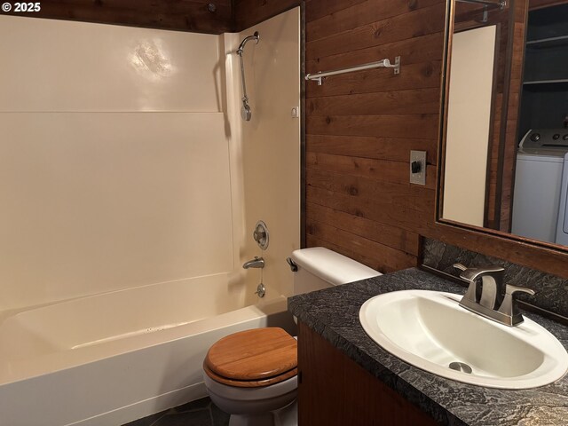 full bathroom with wooden walls, washer / clothes dryer, vanity,  shower combination, and toilet