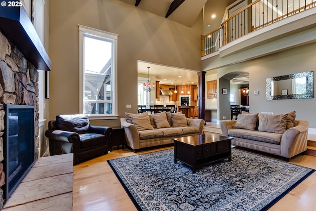 83500 Enterprise Rd, Creswell, OR 97426 - living area with arched walkways, a stone fireplace, light wood-style flooring, decorative columns, and a high ceiling