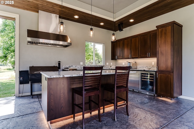 83500 Enterprise Rd, Creswell, OR 97426 - kitchen with wine cooler, wall chimney range hood, dark brown cabinetry, a kitchen island, and light stone countertops
