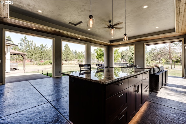 83500 Enterprise Rd, Creswell, OR 97426 - kitchen featuring a tray ceiling, a ceiling fan, dark stone countertops, a kitchen island, and pendant lighting