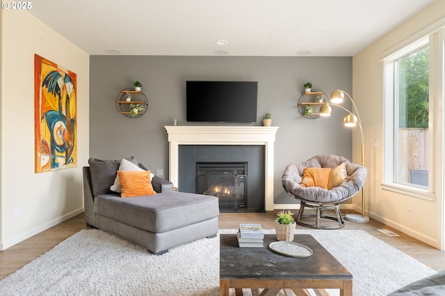 living room featuring a fireplace, wood finished floors, visible vents, and baseboards