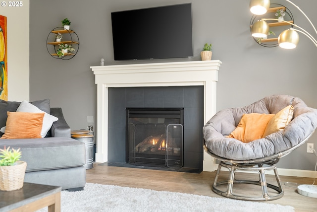 living area with a fireplace, baseboards, and wood finished floors