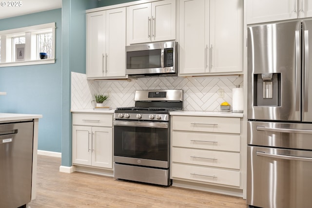 kitchen featuring light wood finished floors, decorative backsplash, stainless steel appliances, and light countertops