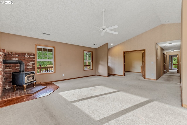 4311 NW 419th St, Woodland, WA 98674 - unfurnished living room featuring light colored carpet, vaulted ceiling, a wood stove, ceiling fan, and a textured ceiling