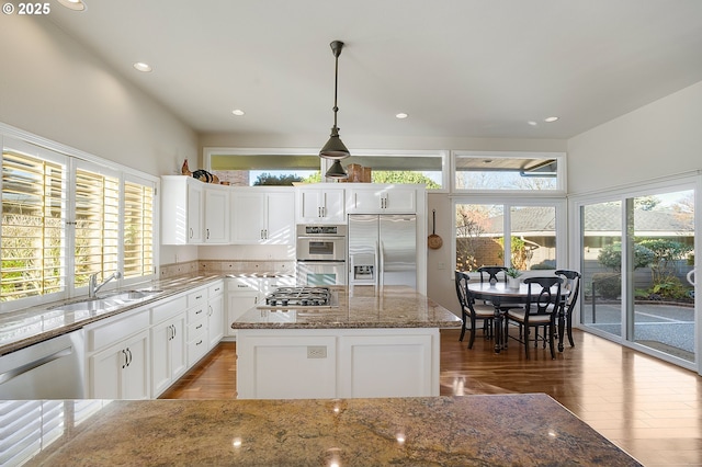 kitchen with a wealth of natural light, stainless steel appliances, sink, pendant lighting, and a kitchen island