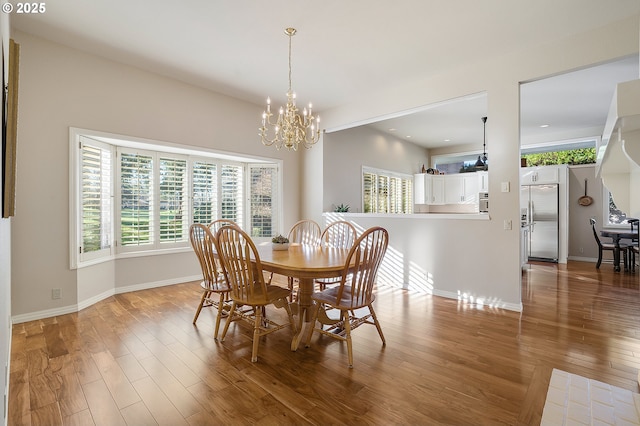 dining room with a chandelier, baseboards, and wood finished floors