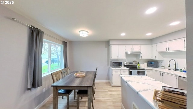 10690 SW Davies Rd Unit 53, Beaverton, OR 97008 - kitchen with stainless steel appliances, a sink, under cabinet range hood, baseboards, and white cabinets