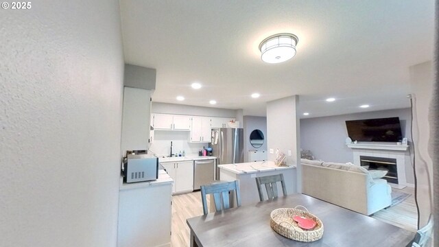 10690 SW Davies Rd Unit 53, Beaverton, OR 97008 - dining area featuring light wood-type flooring, a fireplace, and recessed lighting