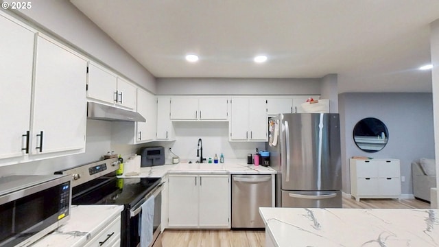 10690 SW Davies Rd Unit 53, Beaverton, OR 97008 - kitchen with stainless steel appliances, under cabinet range hood, a sink, white cabinetry, and light countertops