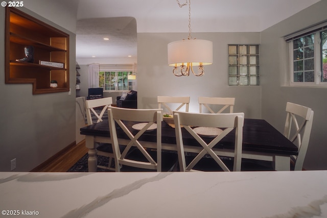 dining space with recessed lighting, wood finished floors, and a notable chandelier