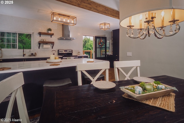 kitchen with stainless steel electric range oven, a sink, light stone counters, a chandelier, and wall chimney exhaust hood