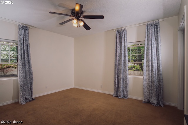 carpeted spare room with plenty of natural light, a ceiling fan, and baseboards