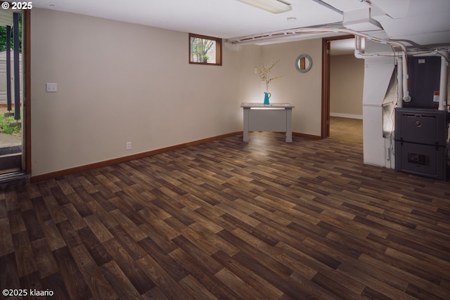 below grade area featuring dark wood-style flooring, baseboards, and heating unit