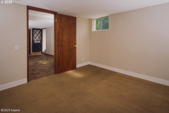 unfurnished room featuring baseboards and dark colored carpet