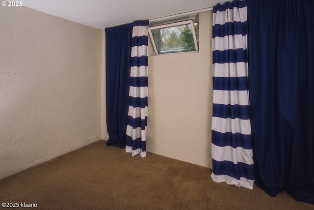 empty room with a textured wall and dark colored carpet