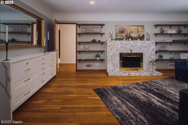 living room featuring recessed lighting, visible vents, wood finished floors, and a high end fireplace