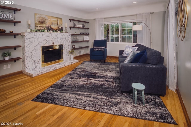 living room with baseboards, recessed lighting, wood finished floors, and a premium fireplace