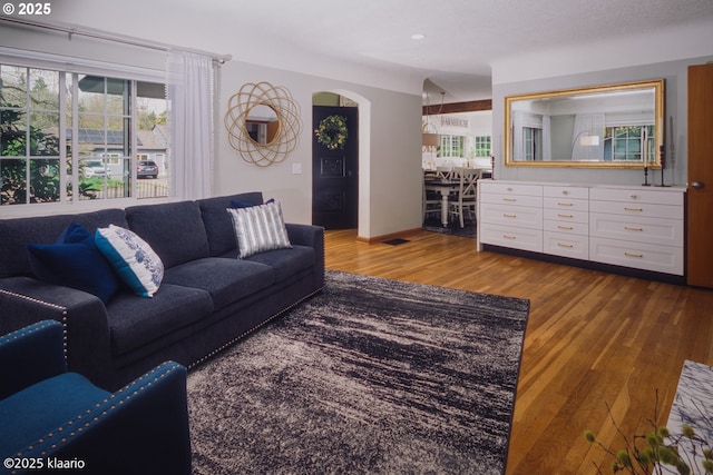 living area featuring recessed lighting, arched walkways, dark wood-style flooring, and baseboards