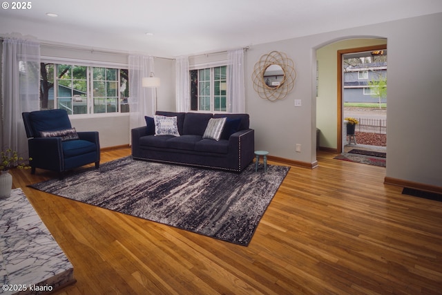 living room featuring arched walkways, baseboards, recessed lighting, and wood finished floors