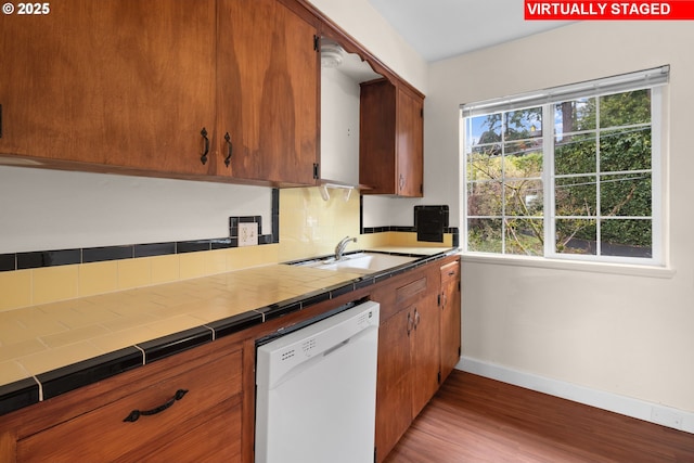 kitchen with dishwasher, light wood-type flooring, tile countertops, and sink