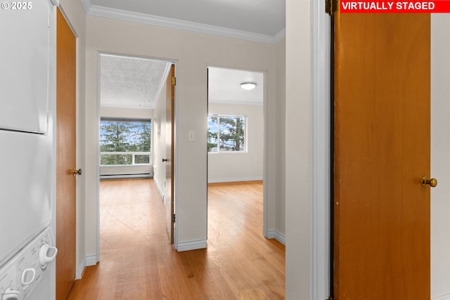 corridor featuring ornamental molding, stacked washing maching and dryer, a baseboard radiator, and light hardwood / wood-style flooring