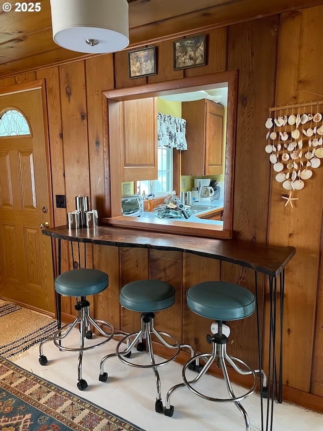 554 N Beacon St, Rockaway Beach, OR 97136 - kitchen with wooden walls, brown cabinetry, a kitchen bar, and dark countertops