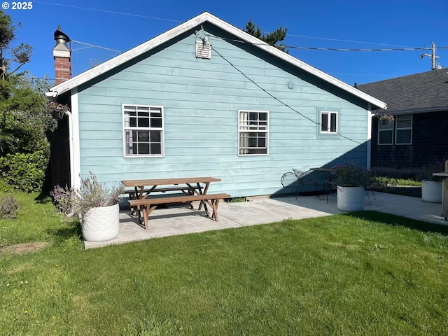 554 N Beacon St, Rockaway Beach, OR 97136 - rear view of property with a lawn, a patio area, and a chimney