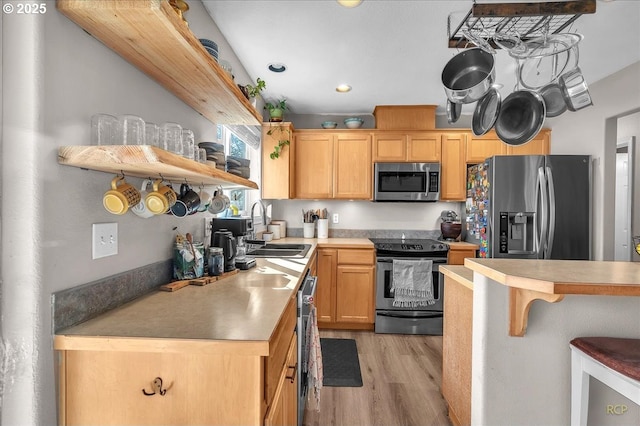 kitchen featuring light wood finished floors, appliances with stainless steel finishes, light countertops, open shelves, and a sink