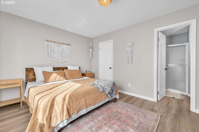 bedroom featuring a spacious closet, baseboards, and wood finished floors