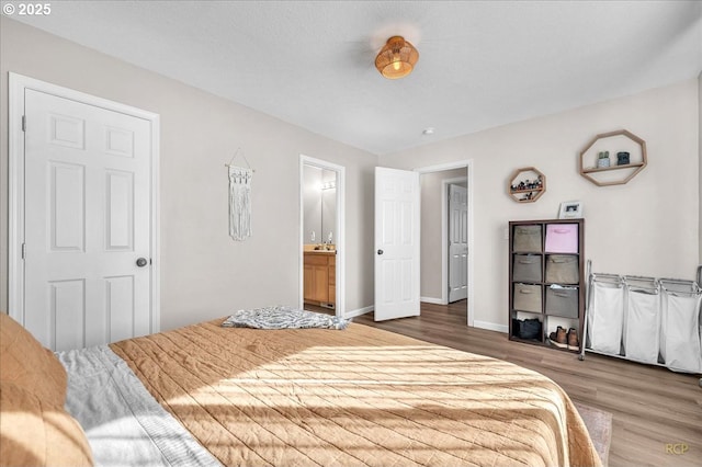 bedroom with wood finished floors, connected bathroom, and baseboards