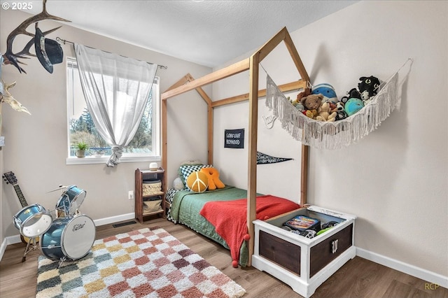 bedroom featuring a textured ceiling, wood finished floors, visible vents, and baseboards