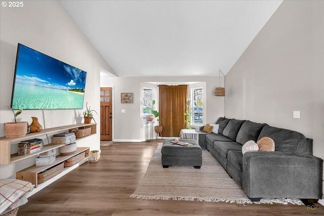 living area featuring high vaulted ceiling, wood finished floors, and baseboards