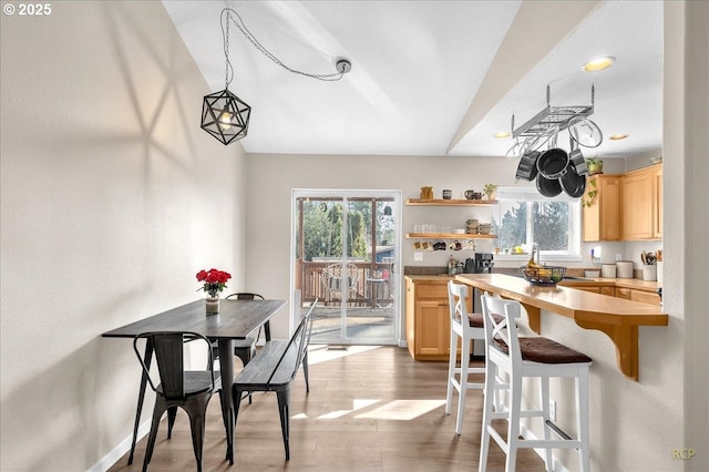 kitchen featuring a breakfast bar, plenty of natural light, light wood-style flooring, and light brown cabinetry