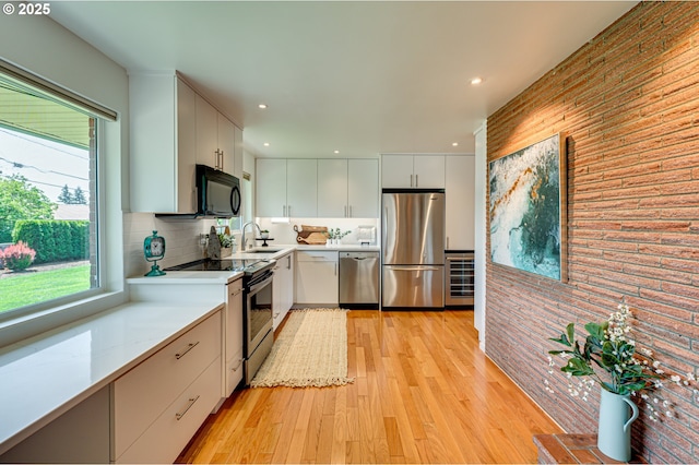 607 W 35th St, Vancouver, WA 98660 - kitchen featuring stainless steel appliances, light countertops, light wood-style flooring, white cabinetry, and decorative backsplash