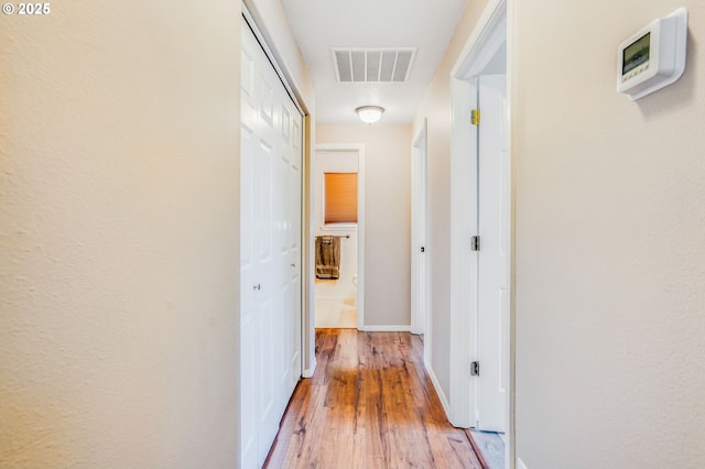hall with light wood-style floors and baseboards
