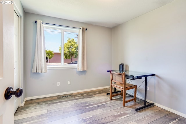 unfurnished office featuring wood finished floors and baseboards