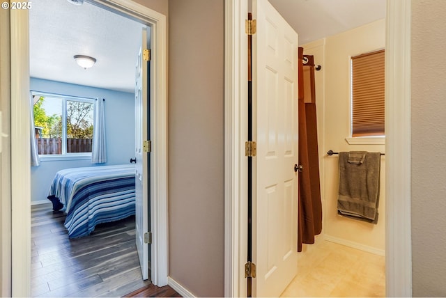 corridor featuring baseboards and wood finished floors