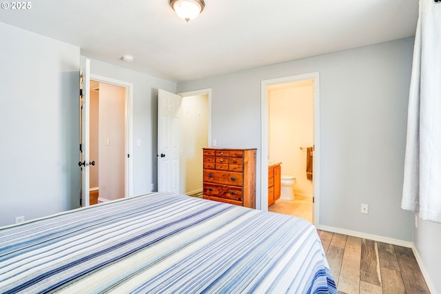 bedroom featuring light wood-style floors, baseboards, and ensuite bathroom