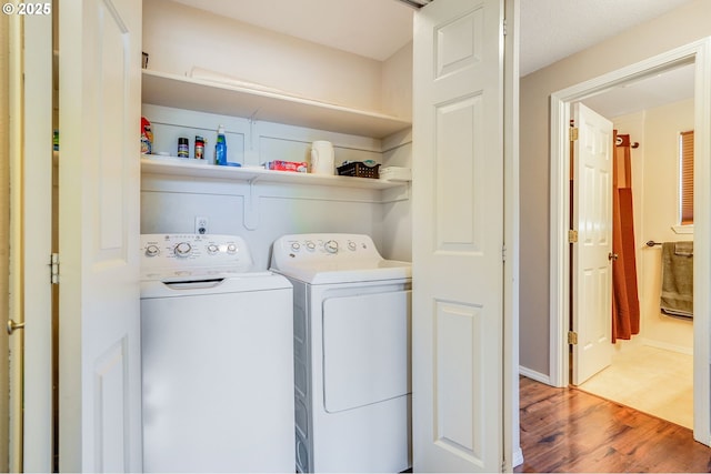 washroom with washing machine and clothes dryer and wood finished floors