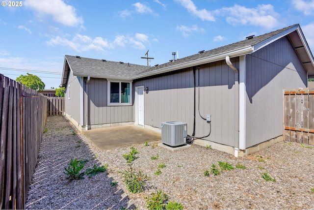 rear view of house featuring central AC unit, a fenced backyard, a patio area, and a shingled roof