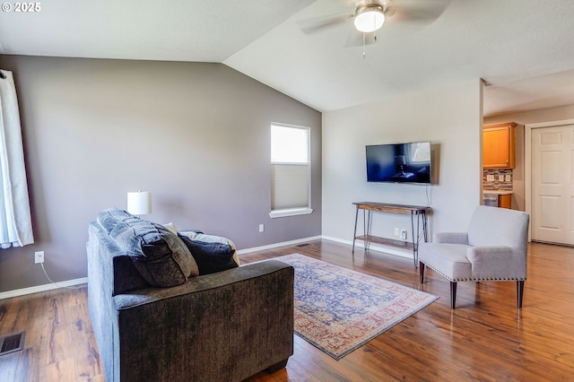 living room featuring ceiling fan, baseboards, vaulted ceiling, and wood finished floors